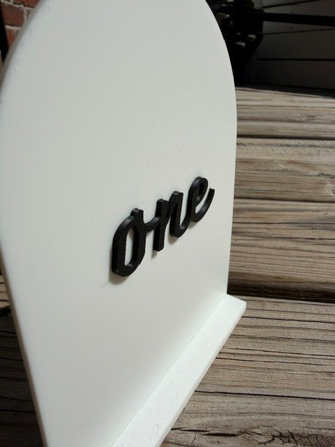 Close-up of black arch table number showing modern design and matte finish